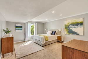 Bedroom with light carpet, crown molding, and a textured ceiling