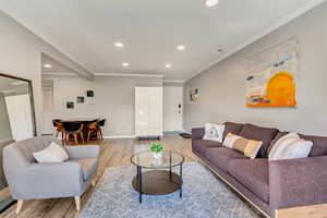 Living room with crown molding and laminate flooring