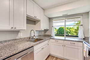 Kitchen featuring light wood-type flooring, appliances with stainless steel finishes, white cabinetry, and sink