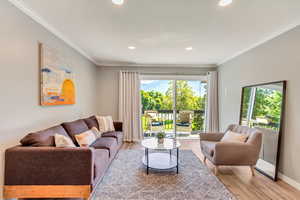 Living room with crown molding, plenty of natural light, and laminate floors