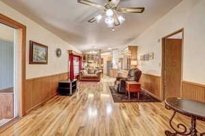 Living room with ceiling fan with notable chandelier and light hardwood / wood-style floors