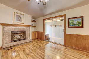 Unfurnished living room with vaulted ceiling, light hardwood / wood-style flooring, a brick fireplace, and ceiling fan