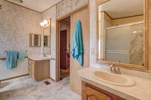 Bathroom with tile patterned flooring, an enclosed shower, ornamental molding, and vanity