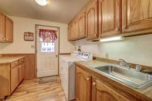 Clothes washing area featuring light wood-type flooring, independent washer and dryer, sink, cabinets, and a textured ceiling