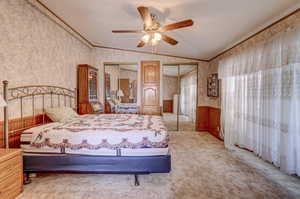 Carpeted bedroom with ceiling fan, crown molding, and vaulted ceiling