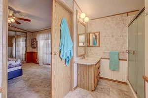 Bathroom featuring vanity, vaulted ceiling, a shower with shower door, and ceiling fan