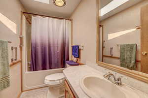 Full bathroom with tile patterned floors, toilet, shower / bath combo with shower curtain, and vanity