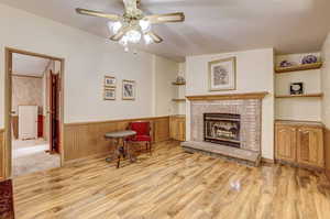 Living room with a fireplace, ceiling fan, and light colored carpet