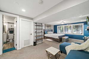 Carpeted bedroom featuring a textured ceiling and ensuite bathroom