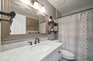 Bathroom with a textured ceiling, vanity, toilet, and a shower with shower curtain