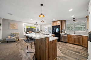 Kitchen with a center island, hardwood / wood-style floors, stainless steel dishwasher, and decorative light fixtures