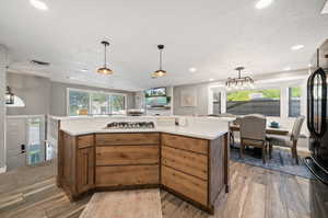 Kitchen featuring pendant lighting, a textured ceiling, hardwood / wood-style floors, and stainless steel gas cooktop