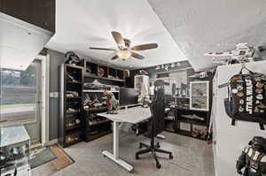 Home office with a textured ceiling, ceiling fan, and light colored carpet