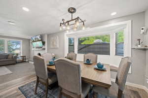 Dining area with a textured ceiling, an inviting chandelier, and hardwood / wood-style floors