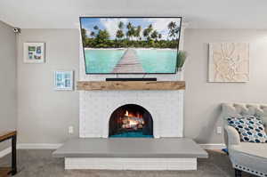 Details with a textured ceiling, a brick fireplace, and carpet floors