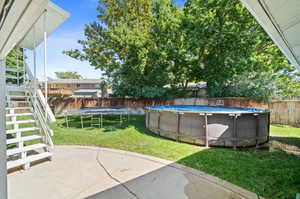 View of yard with a fenced in pool and a trampoline