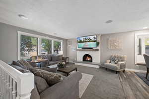 Living room featuring hardwood / wood-style floors, brick wall, a textured ceiling, and a brick fireplace