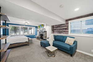 Bedroom featuring a textured ceiling, carpet floors, and a stone fireplace