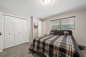 Bedroom featuring a textured ceiling, carpet flooring, and a closet