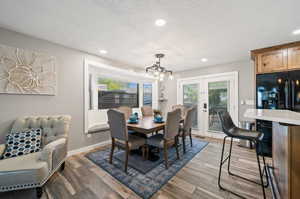 Dining room with french doors, dark hardwood / wood-style floors, a notable chandelier, and a textured ceiling