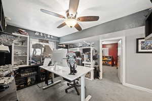 Office with ceiling fan, light carpet, and a textured ceiling