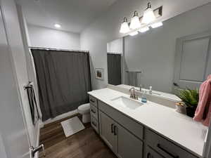 Bathroom featuring vanity, toilet, hardwood / wood-style flooring, and walk in shower