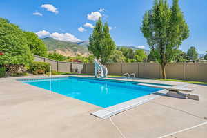 View of swimming pool featuring a water slide, a diving board, a mountain view, and a patio area