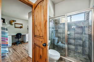 Bathroom with toilet, hardwood / wood-style flooring, and a shower with door