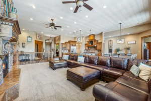 Carpeted living room featuring a fireplace and ceiling fan