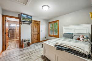 Bedroom with light wood-type flooring, connected bathroom, and a textured ceiling