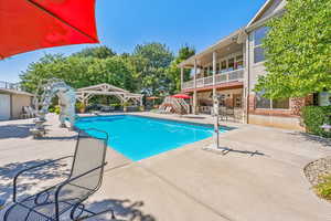 View of pool with a water slide, a patio area, and a gazebo