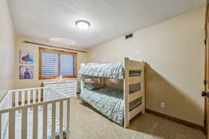 Bedroom featuring a textured ceiling and light carpet