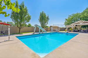 View of pool with an outbuilding, a gazebo, a water slide, a diving board, and a patio