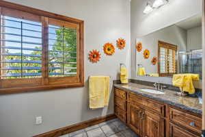 Bathroom featuring tile patterned flooring, vanity, and a shower with shower door