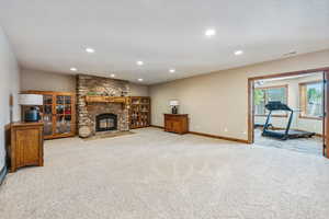 Carpeted living room featuring a textured ceiling and a stone fireplace