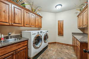 Washroom featuring separate washer and dryer, light tile patterned floors, cabinets, and sink