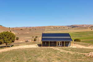 Rear view of house with a rural view, an outdoor structure, and a mountain view