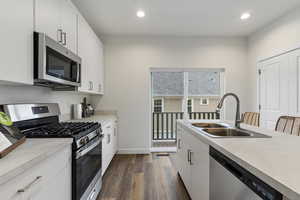 Kitchen featuring appliances with stainless steel finishes, dark hardwood / wood-style flooring, sink, and white cabinets