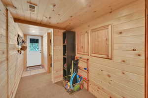 Hall with light carpet, wood ceiling, and wood walls