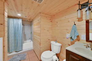 Full bathroom with toilet, tile patterned flooring, vanity, wood walls, and wooden ceiling