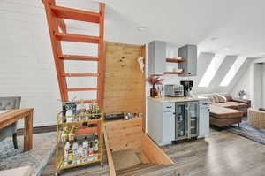 Kitchen with gray cabinets, hardwood / wood-style flooring, wine cooler, and wooden walls