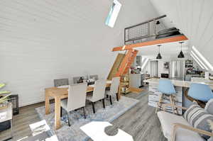 Dining space with a skylight, high vaulted ceiling, light hardwood / wood-style floors, and sink