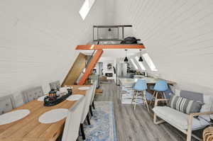 Dining area with hardwood / wood-style flooring and lofted ceiling with skylight