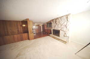 Unfurnished living room with a fireplace, a textured ceiling, wood walls, and dark hardwood / wood-style floors