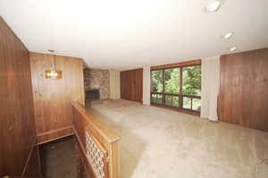 Interior space with a textured ceiling, an inviting chandelier, wooden walls, and a fireplace