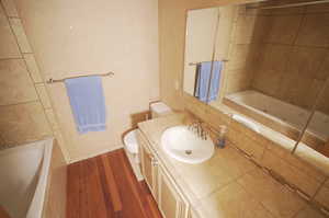 Full bathroom with tiled shower / bath, vanity, toilet, and hardwood / wood-style flooring