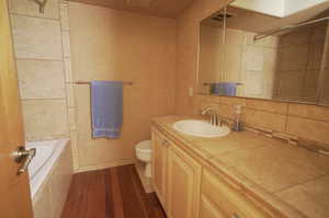 Full bathroom featuring vanity, toilet, tiled shower / bath combo, and hardwood / wood-style flooring