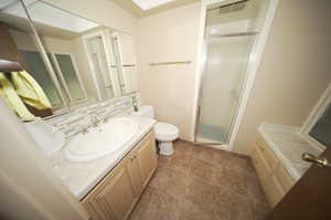 Master Bathroom with vanity, toilet, walk in shower, and tile patterned flooring