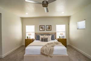 Bedroom with multiple windows, ceiling fan, and carpet floors