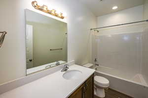 Full bathroom featuring tiled shower / bath combo, vanity, toilet, and hardwood / wood-style flooring